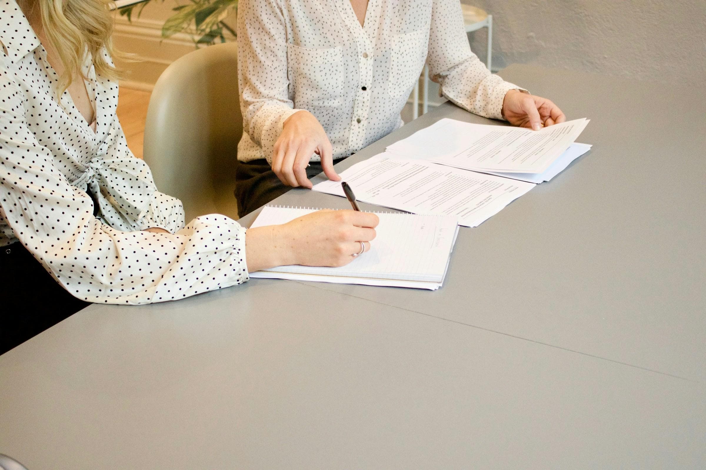 Two colleagues reviewing and annotating printed documents at a desk