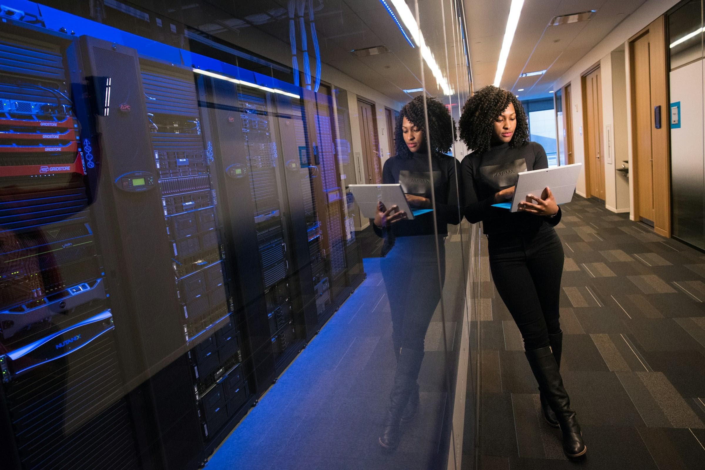 IT professional with a laptop standing beside server racks in a data centre